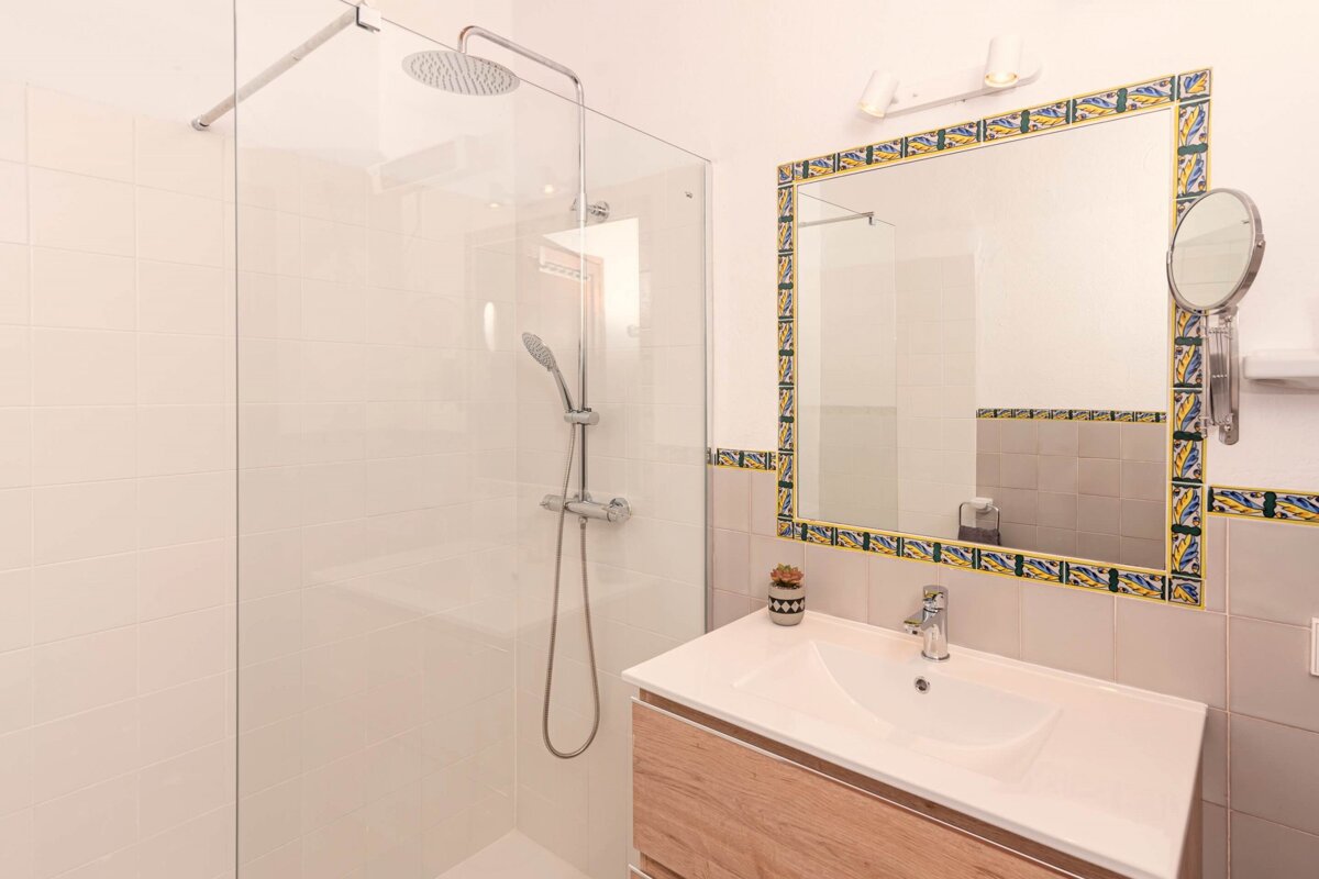 A bathroom with a walk in shower and a sink