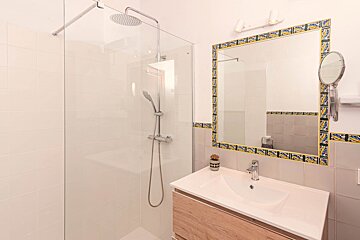 A bathroom with a walk in shower and a sink