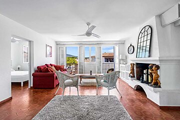 A living room with a red couch and white chairs
