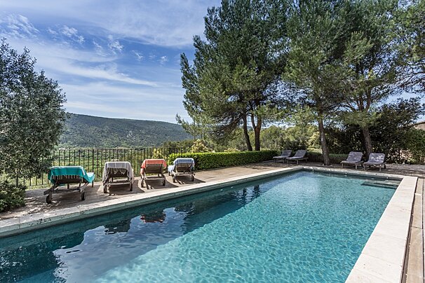 A large swimming pool surrounded by chairs and trees