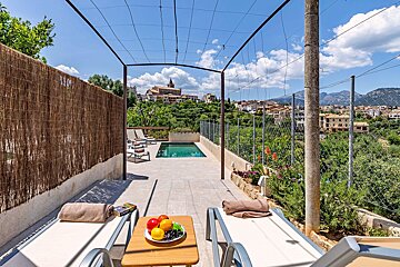 A plate of fruit sits on a table in front of a swimming pool