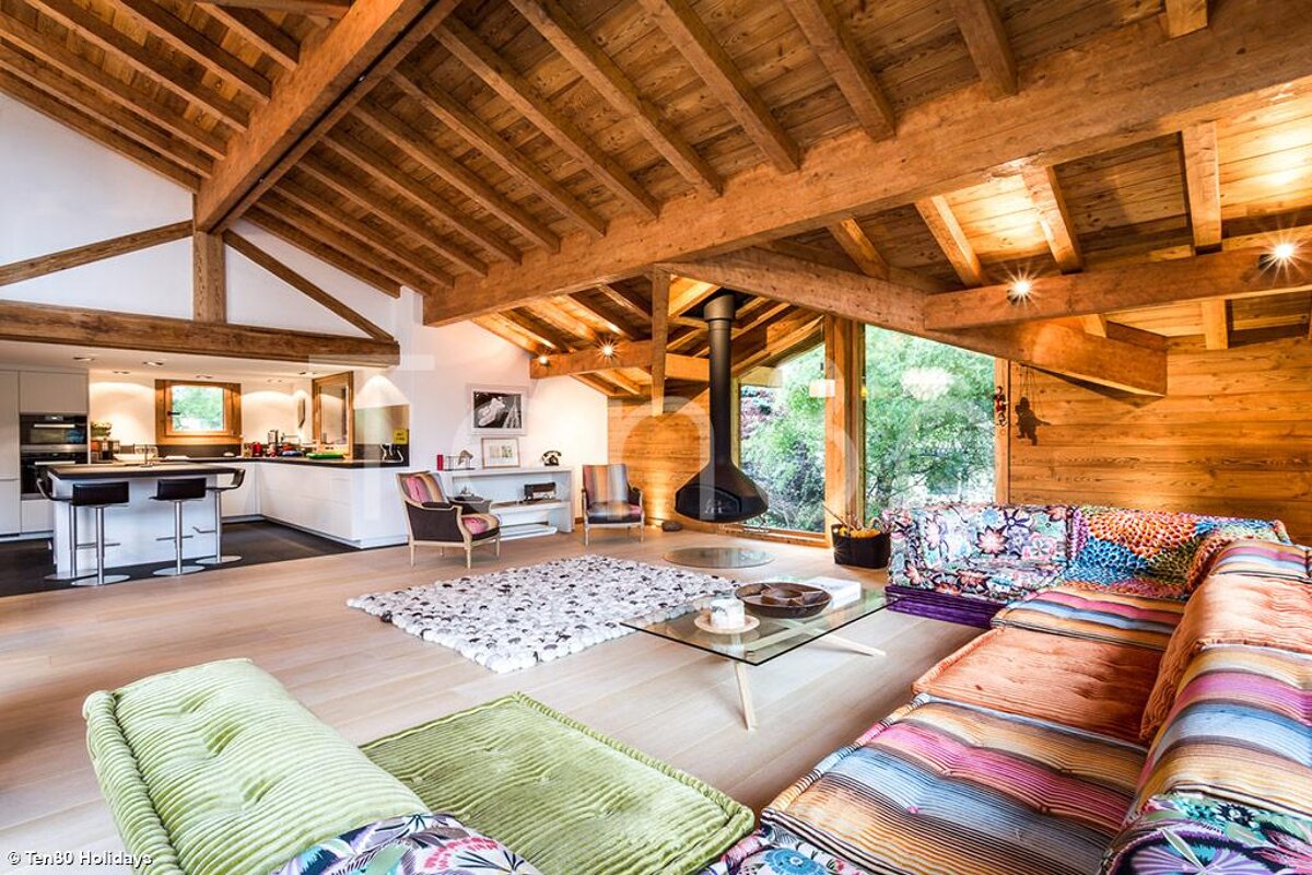 A living room with a colorful couch and a glass coffee table