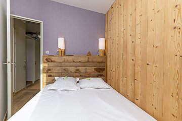 A bedroom with purple walls and wood paneling