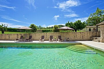 A swimming pool with chairs and umbrellas around it