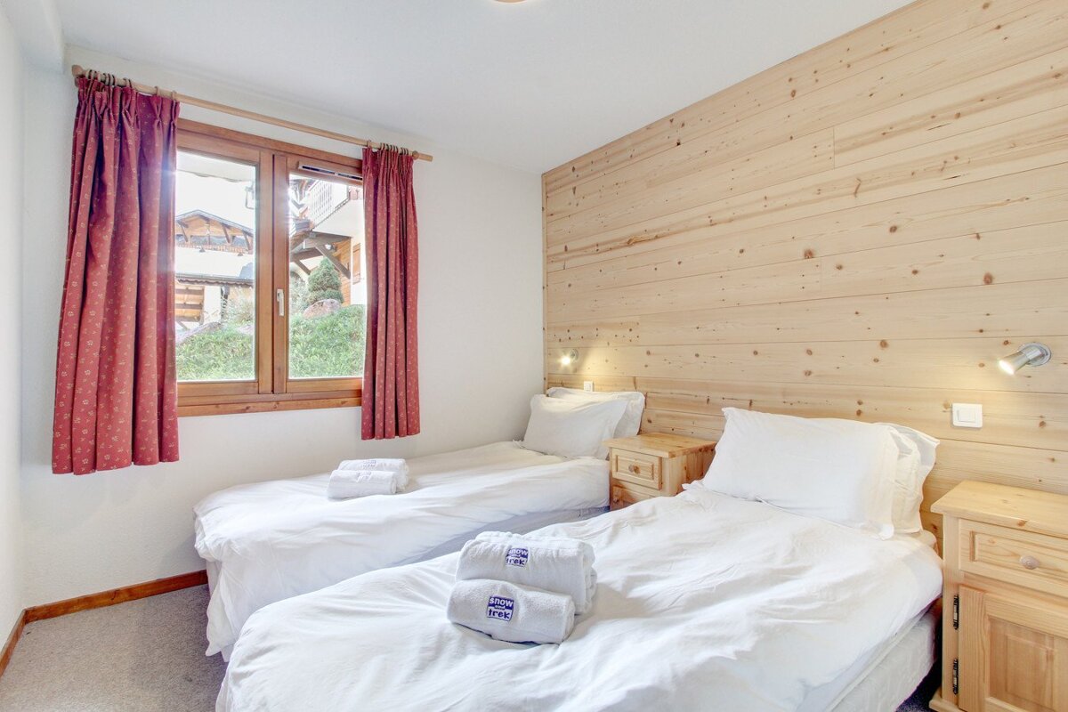 A bedroom with two twin beds and a window
