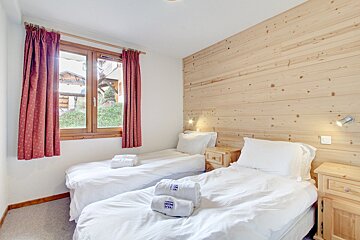 A bedroom with two twin beds and a window