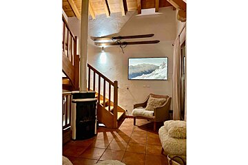 A living room with stairs a chair and a television
