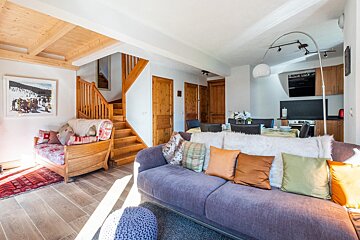 A living room with a couch and chair and stairs