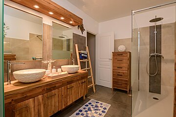 A bathroom with two sinks and a walk in shower