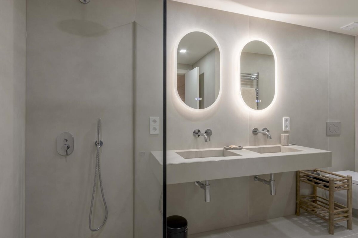 A bathroom with two sinks and oval mirrors
