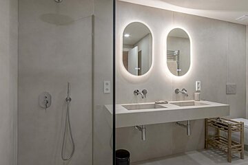 A bathroom with two sinks and oval mirrors