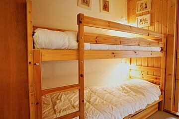 A wooden bunk bed with white sheets and pillows