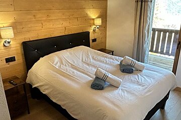 A bedroom with a large bed and a balcony