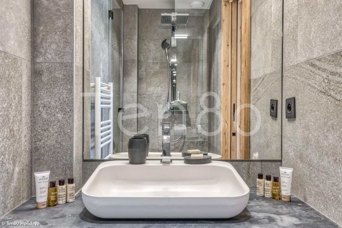 A bathroom with a sink and bottles of nuxe products