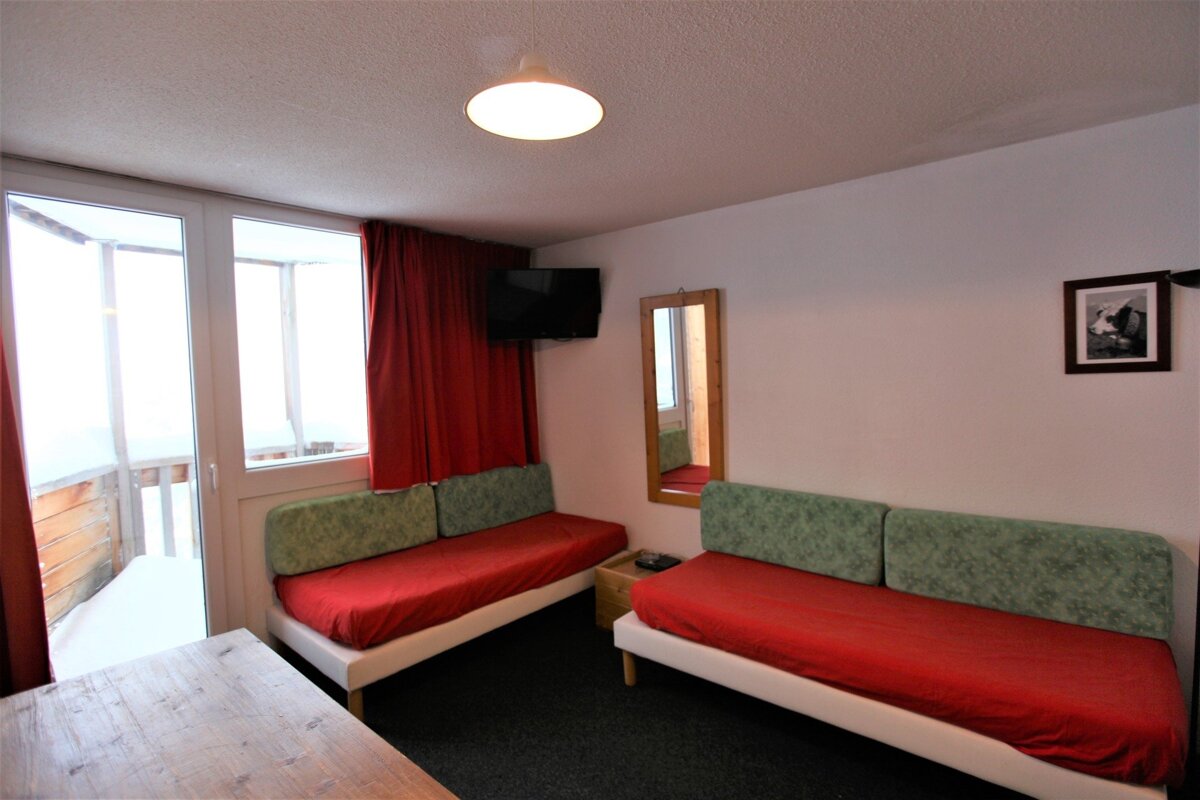 A room with two beds and a television on the wall