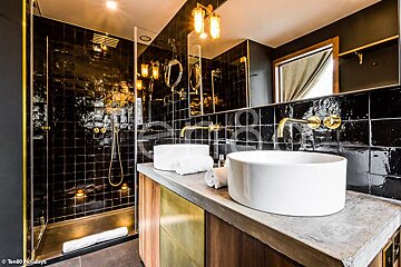 A bathroom with black tiles and two sinks
