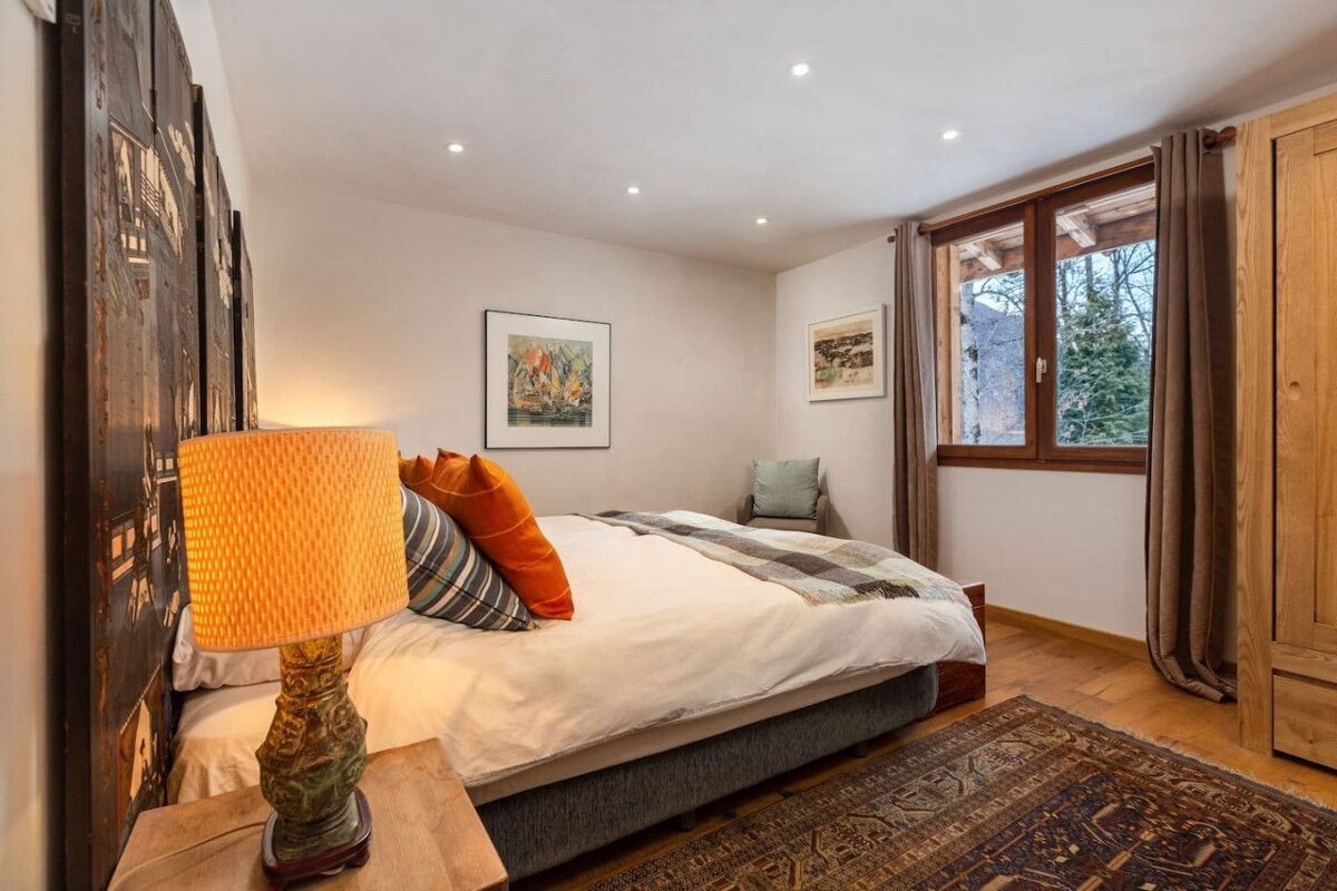 A bedroom with a large bed and a lamp