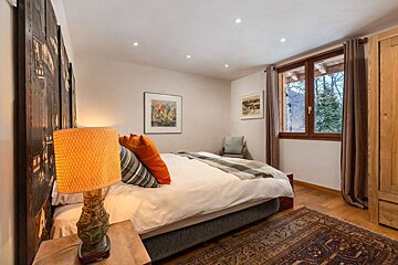 A bedroom with a large bed and a lamp
