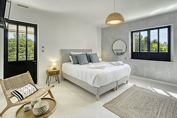 A bedroom with a large bed and a chair