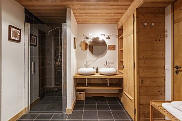 A bathroom with two sinks and a walk in shower