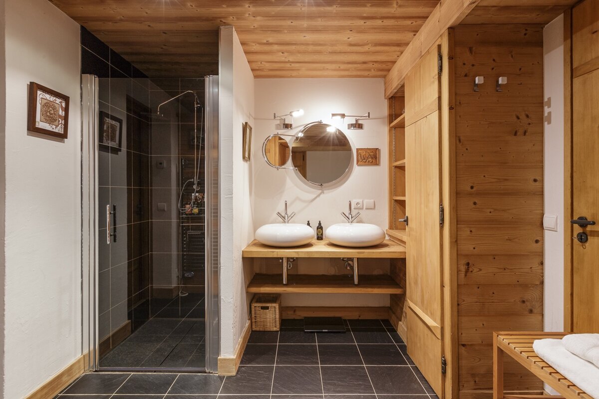 A bathroom with two sinks and a walk in shower