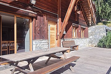 A wooden picnic table sits outside of a wooden building