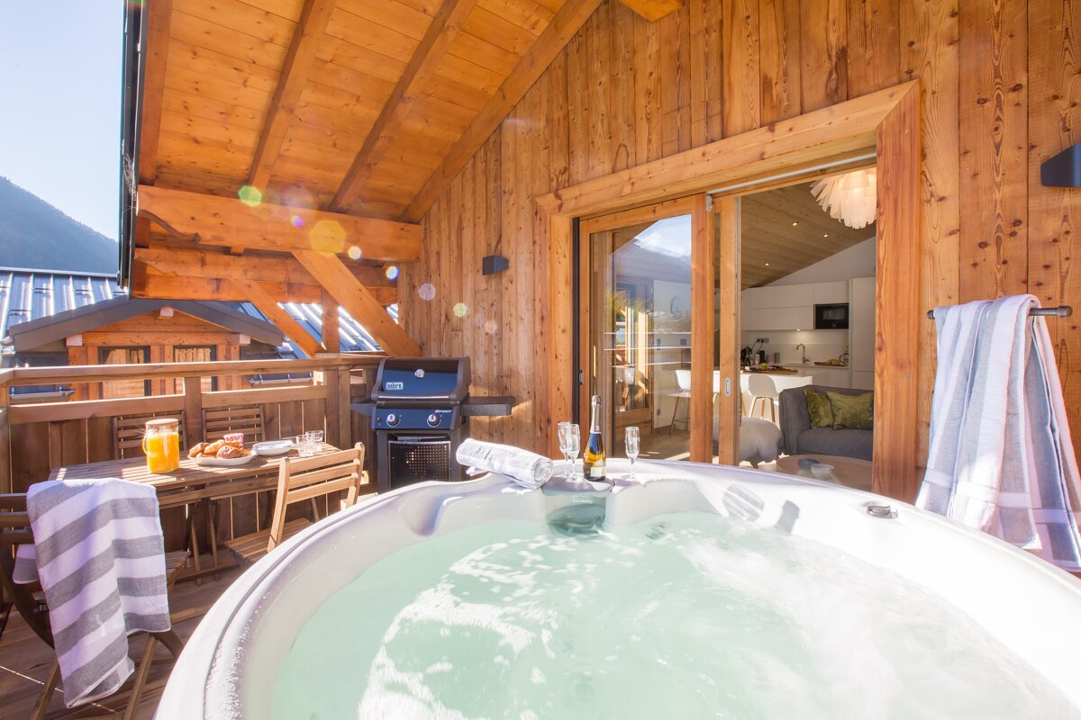A hot tub on a balcony with a bottle of wine