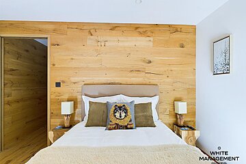 A bedroom with a wooden wall and a white management logo