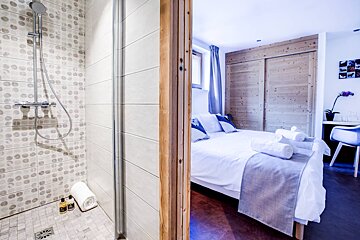 A bathroom with a shower and a bedroom with a bed