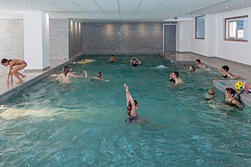 A group of people are swimming in a large indoor pool
