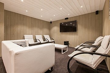 A living room with white chairs and a flat screen tv