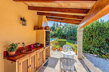 A patio with a table and chairs under a wooden roof