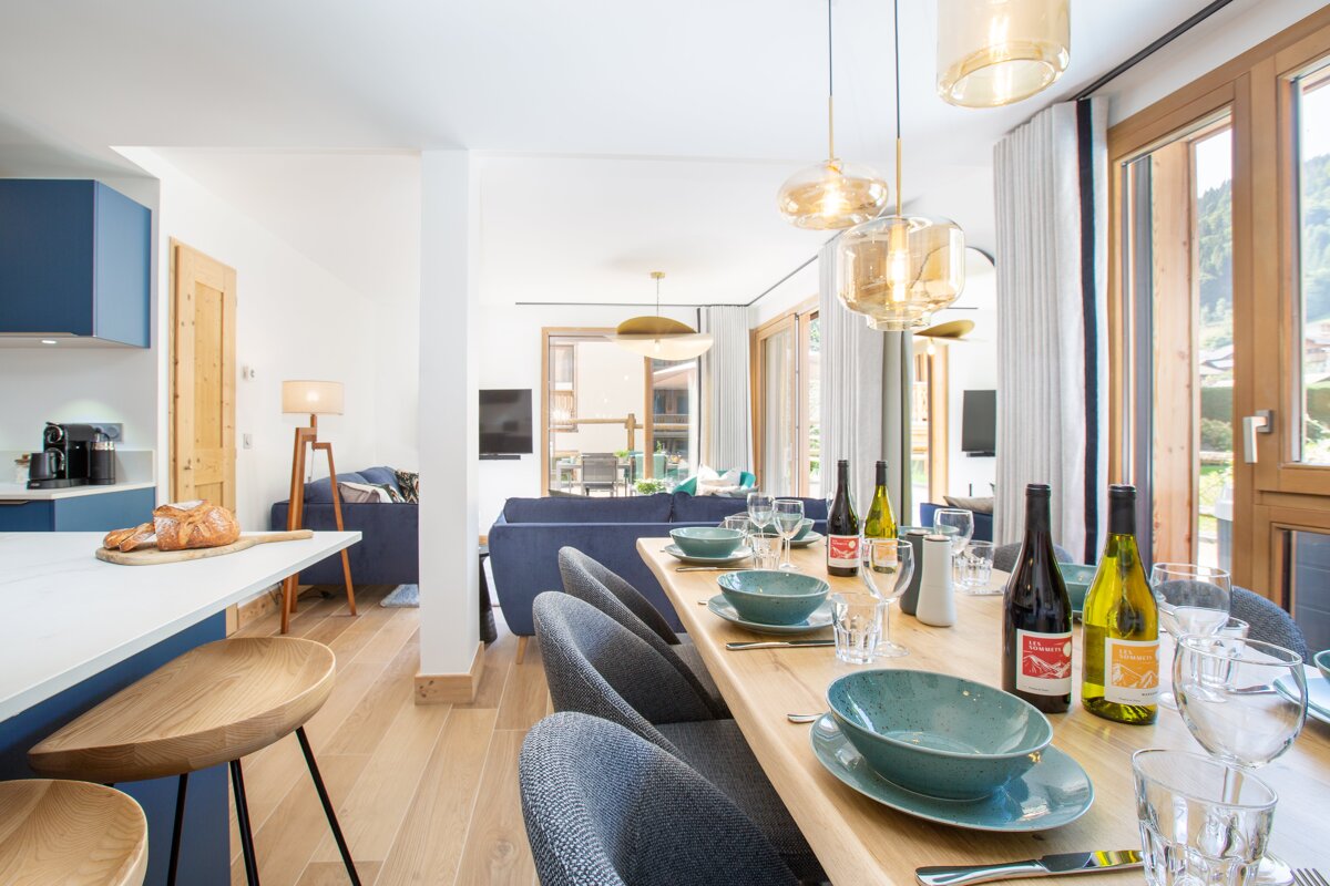 A dining room table with bowls and glasses and bottles of wine