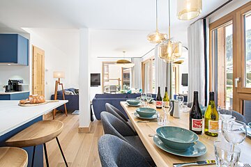 A dining room table with bowls and glasses and bottles of wine