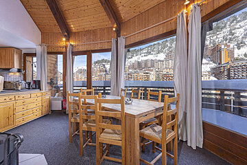 A kitchen with a table and chairs and a view of the mountains