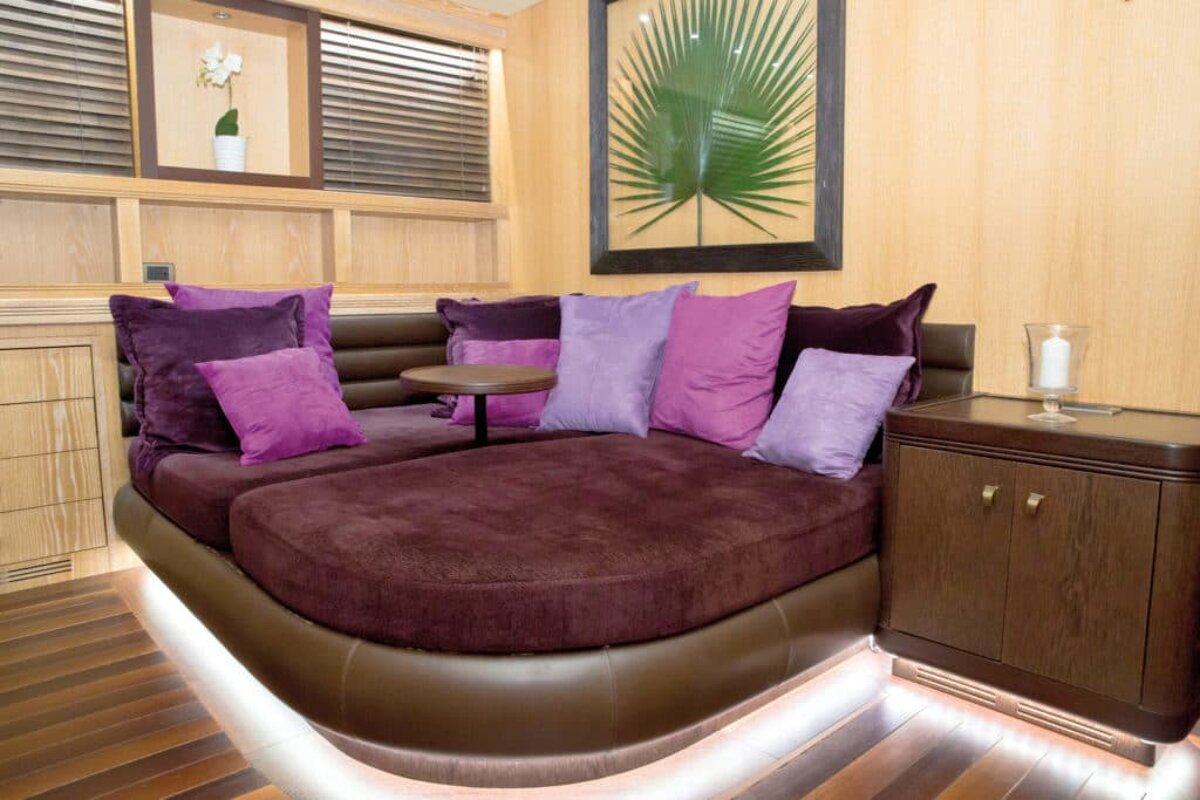 A couch with purple pillows and a picture of a palm tree on the wall