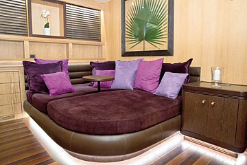 A couch with purple pillows and a picture of a palm tree on the wall