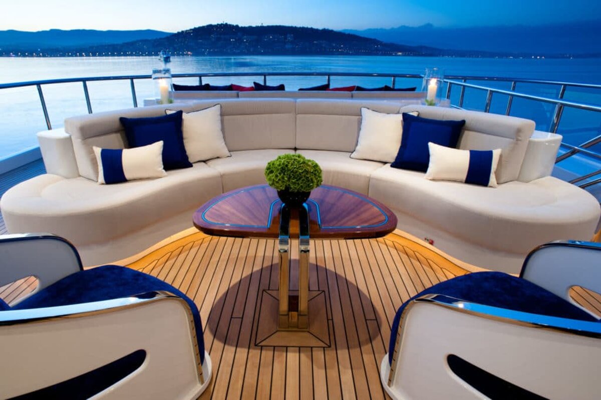 A couch with blue and white pillows sits on the deck of a boat