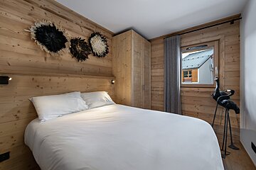 A bedroom with a white bed and a window