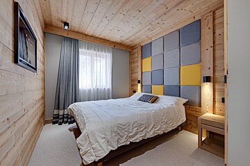 A bedroom with a bed and a television on the wall