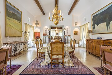 A dining room with a chandelier and a painting of a bull on the wall
