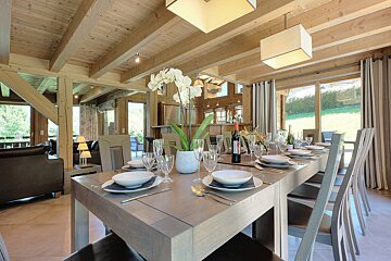 A dining room table with a bottle of wine on it
