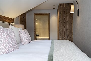 A bedroom with a white bed and pink pillows