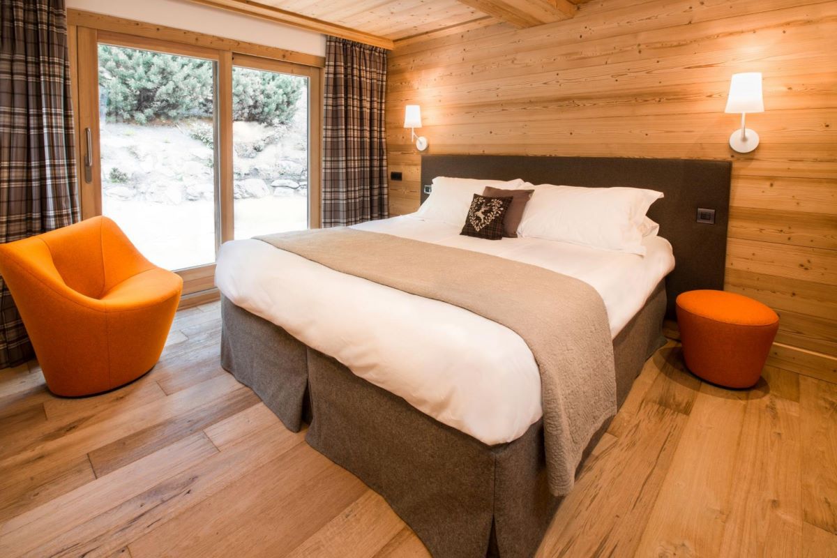 A bedroom with a large bed and a chair