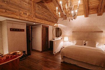 A bedroom with a large bed and a copper bathtub
