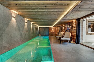 A swimming pool with a wooden ceiling and chairs