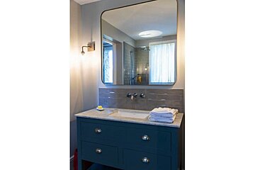 A bathroom with a blue vanity and a large mirror
