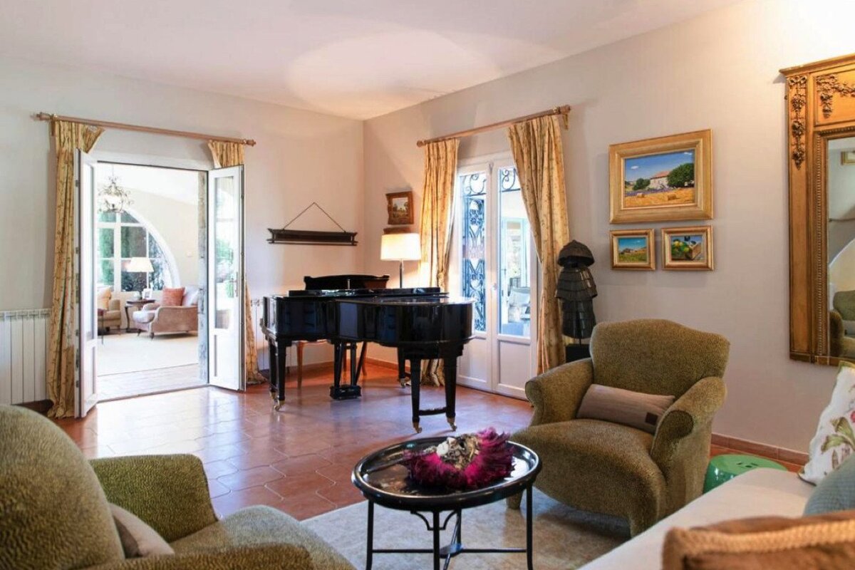 A living room with a piano and paintings on the wall