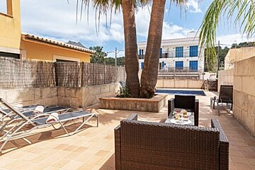 A patio with chairs and a table in front of a pool