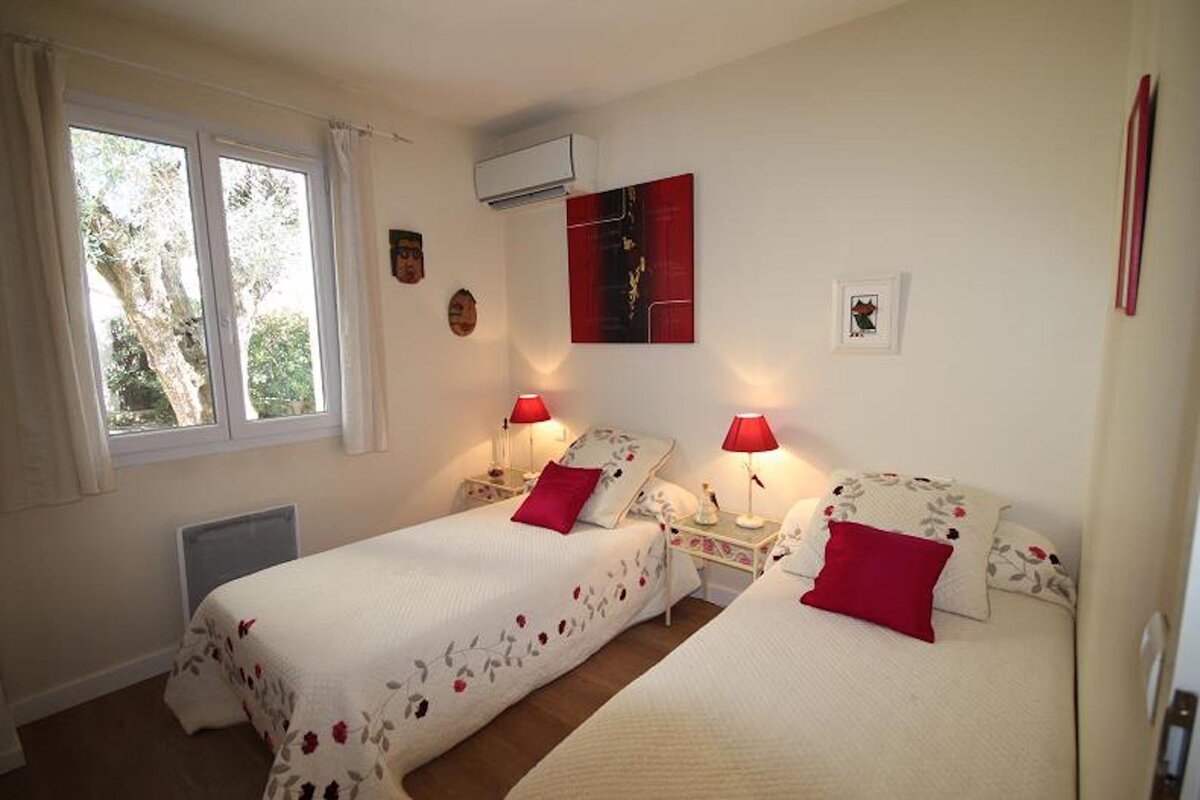 A bedroom with two beds and a painting on the wall